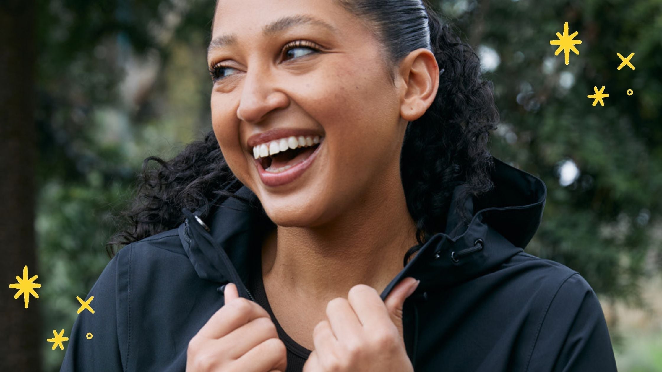 Model wearing the Elements jacket in black while smiling happily and grabbing the collar of the jacket